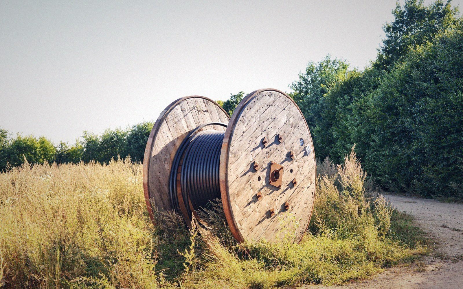 A two-person team feeding cable into a duct from a drum