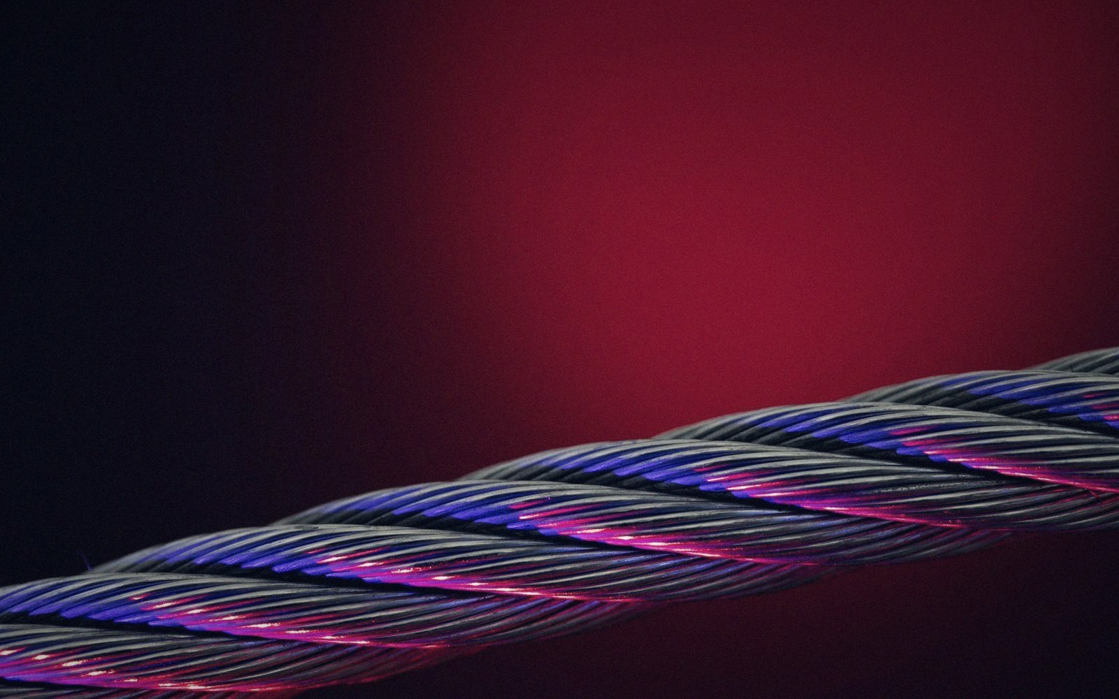 Twisted metal cable with blue and pink light reflecting off its strands