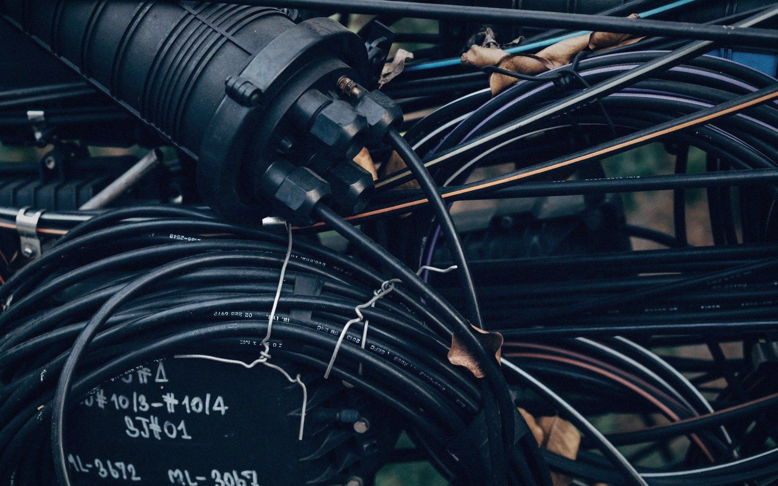 Coiled fiber optic cables connect to a black splice enclosure with handwritten labels