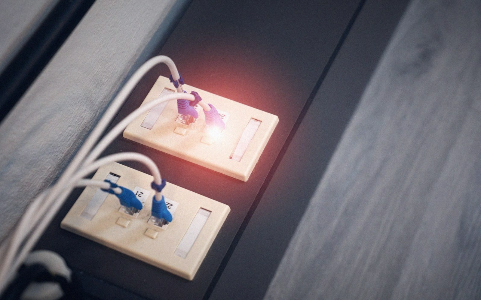 Ethernet cables plugged into wall sockets with a glowing orange light between the ports