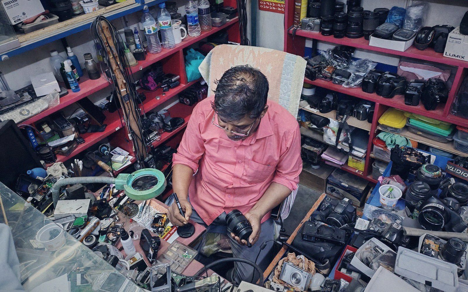 A splicer kneeling at an open joint enclosure with a fusion splicer