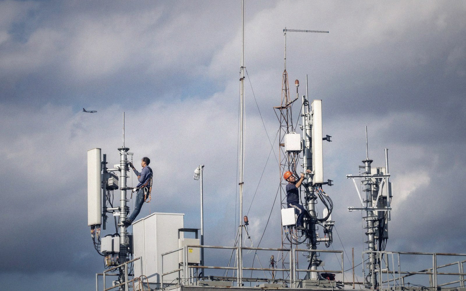 Someone reading a tester screen at the top of a pole